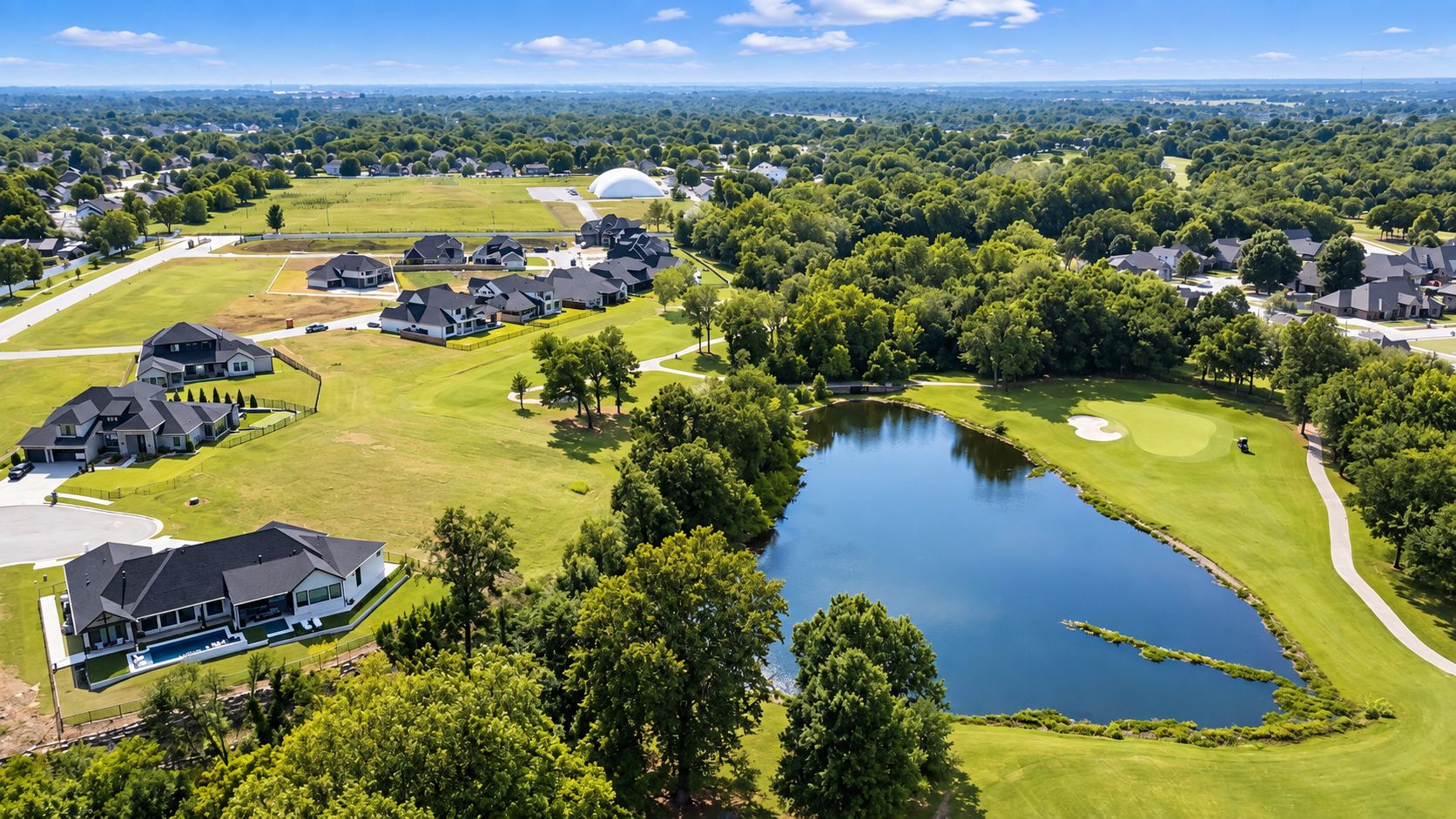 Aerial view of a residential neighborhood beside a golf course pond — Owasso, OK